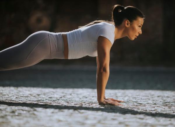 woman doing pushups, co<em></em>ncept of a no-gym workout to melt belly fat